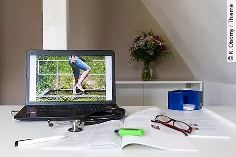 Symbolbild Integrative Medizin, Arztschreibtisch mit Stethoskop und Laptop mit Bild zu Kneipp-Wassertreten