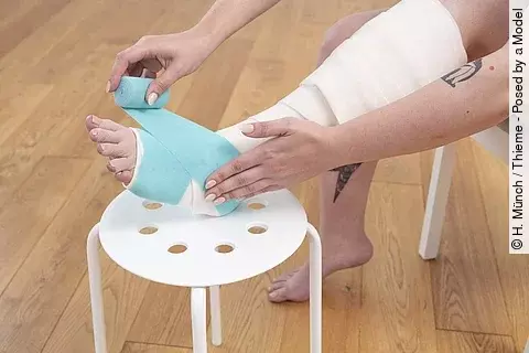 Frau wickelt sich die Beine mit Kompressionsbinden