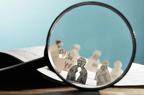 Lupe hält vor Figuren aus Zeitung