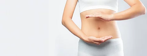 Frau formt mit ihren Händen einen Kreis um den Bauch. 