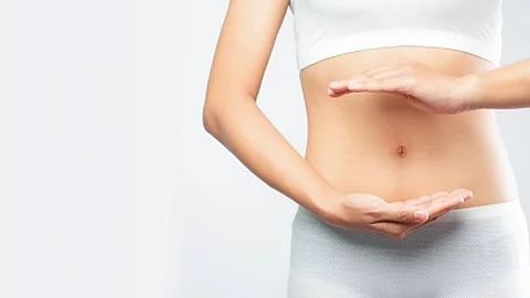 Frau formt mit ihren Händen einen Kreis um den Bauch. 