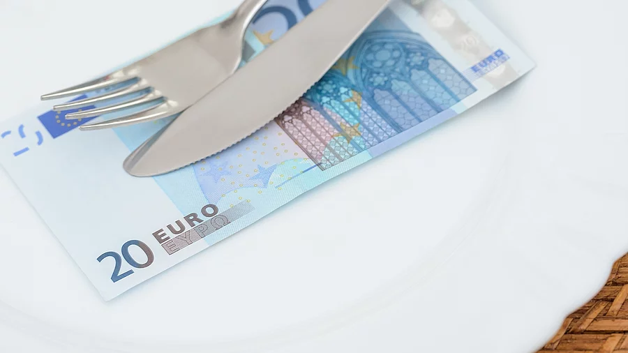 Auf einem Teller liegt ein 20 €-Schein. Darüber liegen Messer und Gabel.