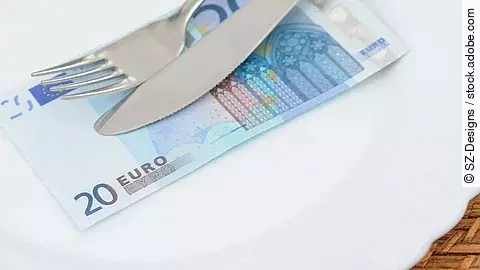 Auf einem Teller liegt ein 20 €-Schein. Darüber liegen Messer und Gabel.