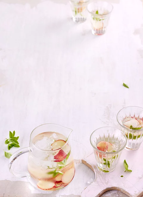 Gläser mit Infused Water mit Nektarinenscheiben und Basilikum