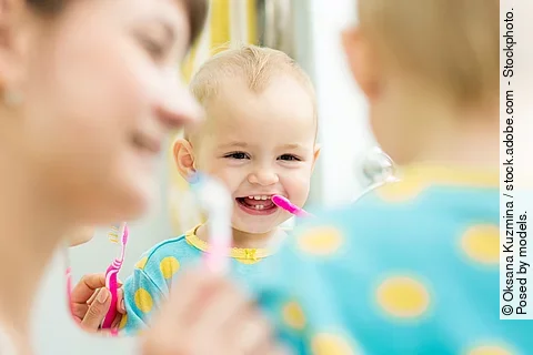 Mutter zeigt ihrem Kleinkind das Zähneputzen