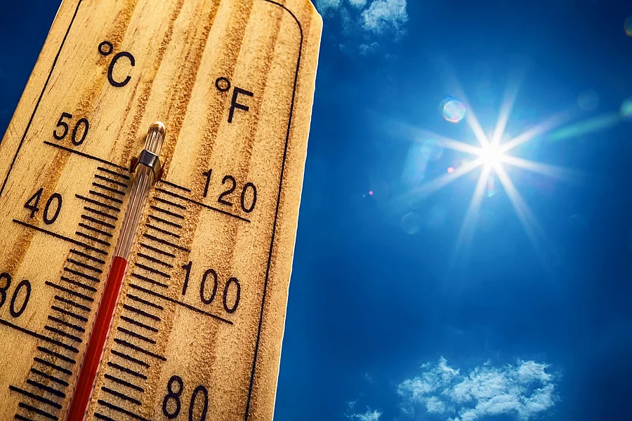 Thermometer mit Himmel und Sonne im Hintergrund.