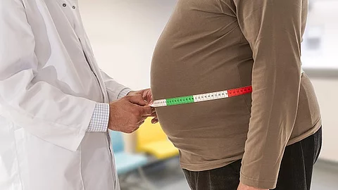 Arzt misst Bauchumfang bei adipösem Patienten.