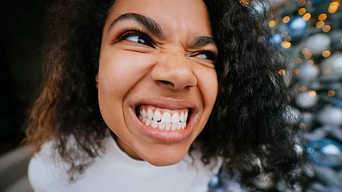 Eine Frau grinst angestrengt nahe der Kamera