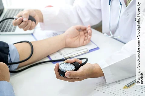 Ein Arzt checkt den Blutdruck eines Patienten.