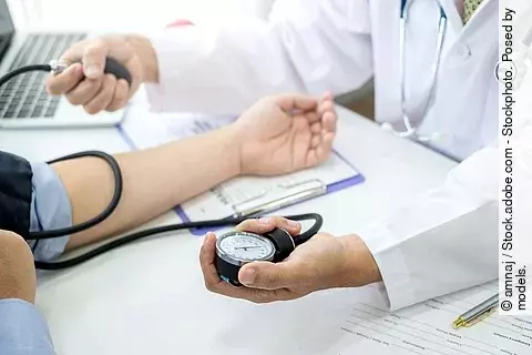 Ein Arzt checkt den Blutdruck eines Patienten.