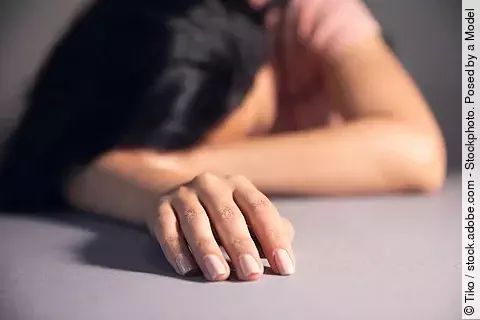 Frau erschöpft mit dem Kopf auf dem Schreibtisch