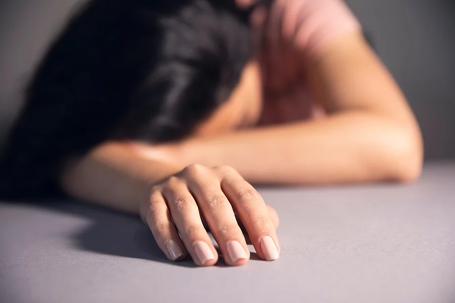 Frau erschöpft mit dem Kopf auf dem Schreibtisch