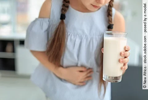 Little girl with dairy allergy holding glass of milk indoors