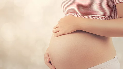 Schwangere Frau hält sich den Bauch