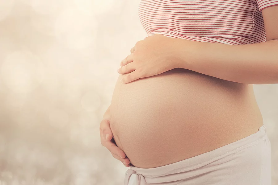 Schwangere Frau hält sich den Bauch