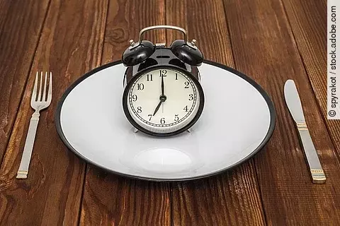 Intervallfasten, Wecker auf leerem weißen Teller