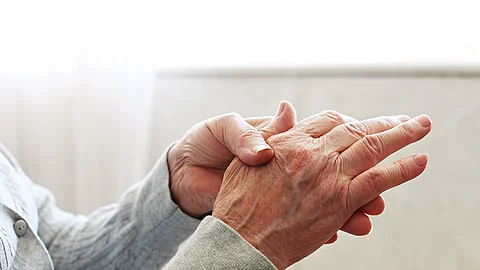 Seniorin massiert ihre rechte Hand.