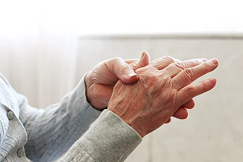 Seniorin massiert ihre rechte Hand. 