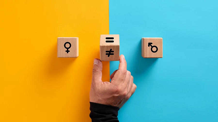 2 Holzklötzchen mit Symbol für weiblich und männlich. Eine Hand dazwischen dreht einen Würfel von = auf ungleich 2 Holzklötzchen mit Symbol für weiblich und männlich. Eine Hand dazwischen dreht einen Würfel von = auf ungleich