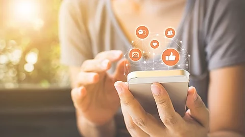 Frau, die ihr Smartphone benutzt und drum herum erscheinen Icons (Facebook, E-Mail, Messenger)