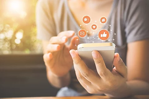Frau, die ihr Smartphone benutzt und drum herum erscheinen Icons (Facebook, E-Mail, Messenger)
