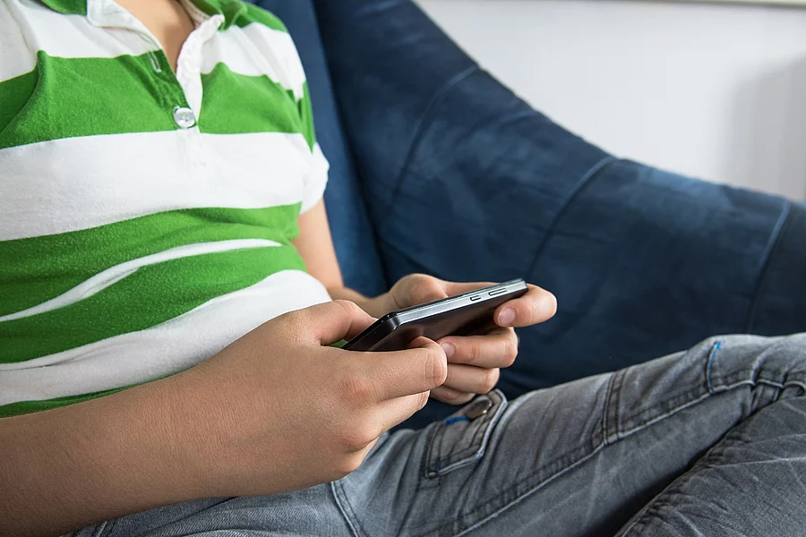 Sitzender Junge spielt auf dem Handy. Sitzender Junge spielt auf dem Handy.