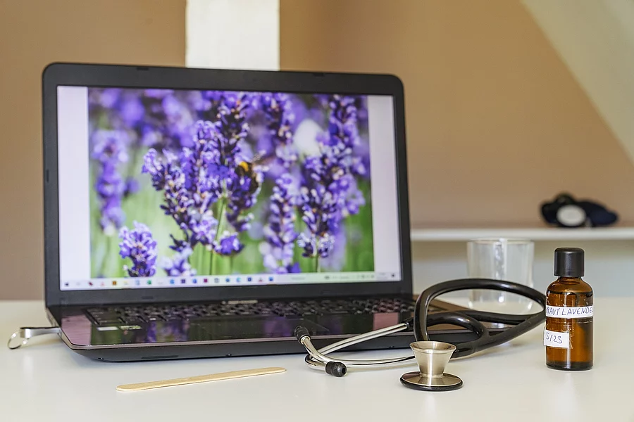 Symbolbild Komplementärmedizin, Schreibtisch mit Laptop, Lavendel und Blutdruckmessgerät