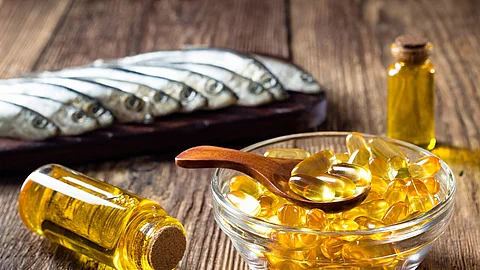 Fish oil capsules on wooden background, vitamin D supplement Fischölkapseln und kleine Fische auf Holzuntergrund