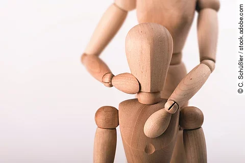 Holzfigur führt osteopathische Behandlung bei Holzfigur aus