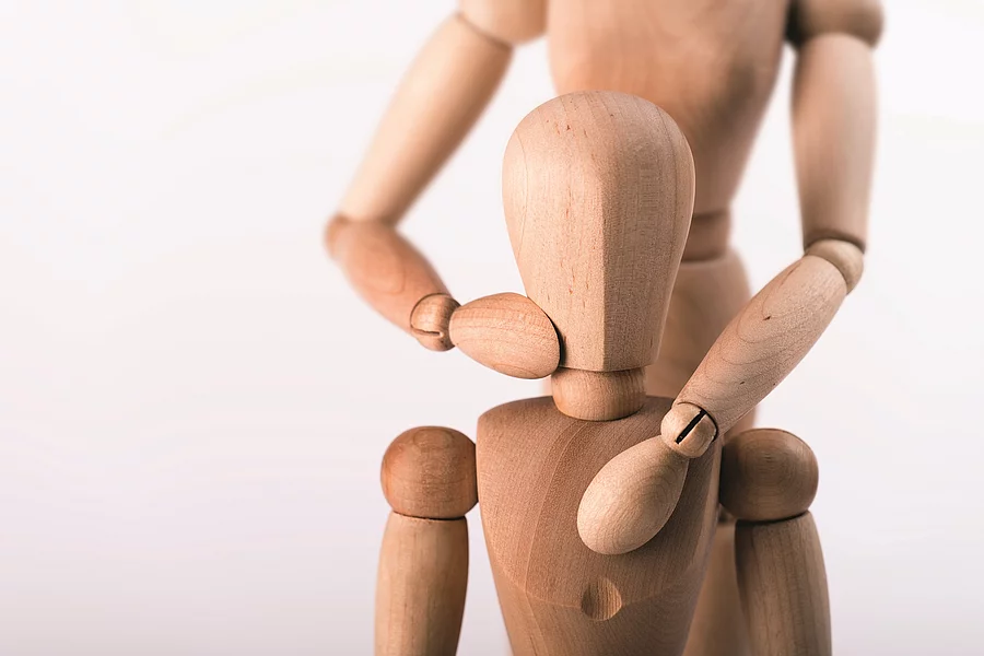Holzfigur führt osteopathische Behandlung bei Holzfigur aus