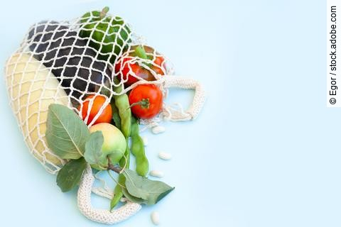 Obst und Gemüse in weißer Einkaufstasche aus Strick.