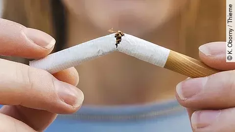 Eine Frau bricht eine Zigarette in der Mitte durch.