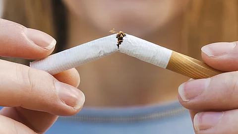 Eine Frau bricht eine Zigarette in der Mitte durch.