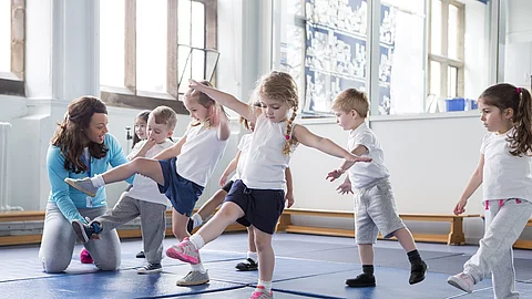 Kinder und Lehrerin in einer Turnhalle