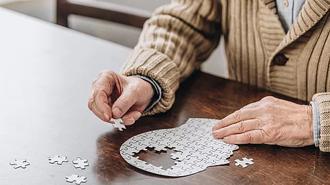 Alte Frau puzzelt einen Kopf, in dem Teile fehlen