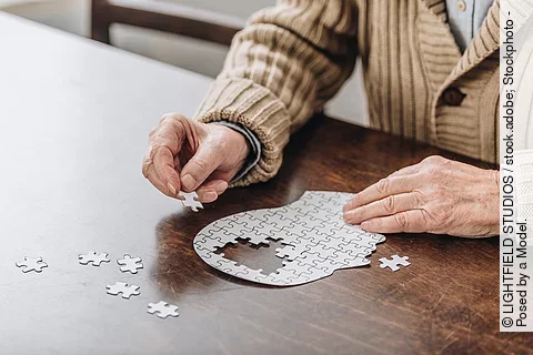 Alte Frau puzzelt einen Kopf, in dem Teile fehlen