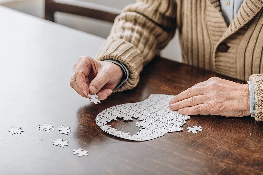 cropped view of senior man playing with puzzles Alte Frau puzzelt einen Kopf, in dem Teile fehlen