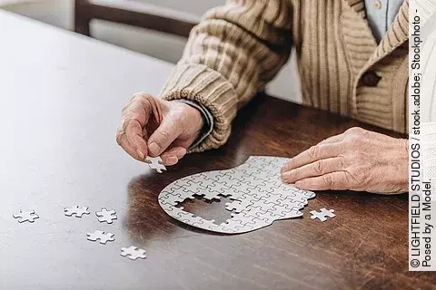 Alte Frau puzzelt einen Kopf, in dem Teile fehlen