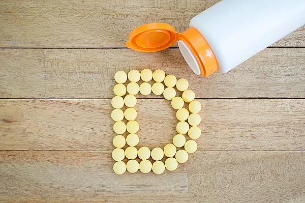 Vitamin D, gelbe Pillen zum D gelegt auf Holz