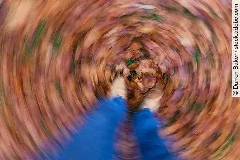 Dreh-Schwindel mit Blick auf Beine im Laub stehend