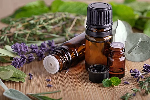 Lavendelblüten, Salbeiblätter und Aromaöl-Braunfläschchen auf Holzuntergrund