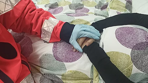 Eine Rettungskraft hält die Hände einer älteren Person am Bett.