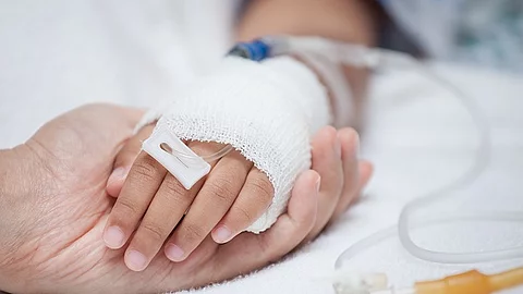 Mutter hält Kinderhand mit Infusion