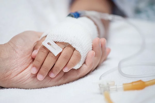 Mutter hält Kinderhand mit Infusion