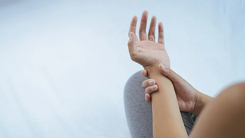 Tremor: Frau hält sich zitternde Hand