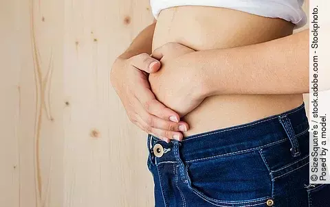 Eine Frau hält sich mit beiden Händen den Bauch fest