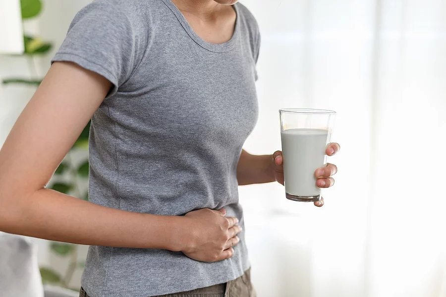Food allergy milk lactose allergen health care illness concept. Frau mit einem Glas Milch in der Hand hält sich den Bauch.