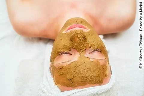 Frau hat eine Heilerdemaske im Gesicht.