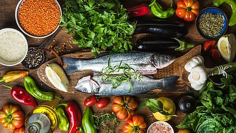 mediterrane Lebensmittel: Fisch, frisches Gemüse, Olivenöl, Hülsenfrüchte, Knoblauch, Zitrone, Kräuter