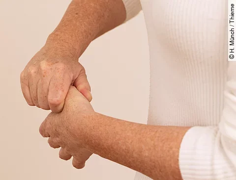 Frau umfasst das Daumensattelgelenk und zieht den Daumen in die Länge